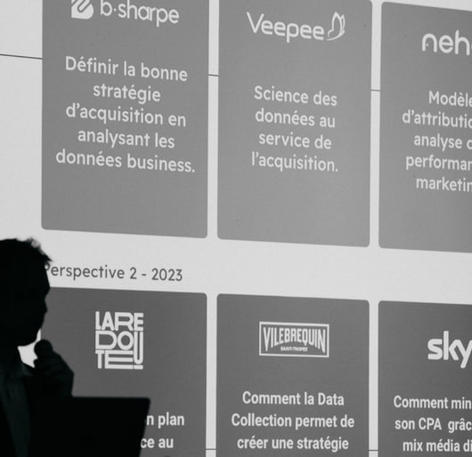 Un intervenant devant l’écran des éditions précédentes : les cas b-Sharpe, Veepee, Neho, Sky et Foxstone.