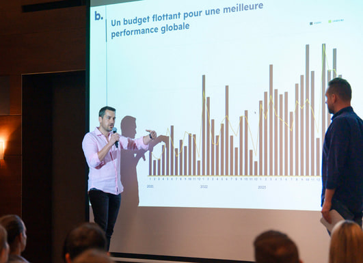 Deux intervenants devant un histogramme de la répartition du budget.