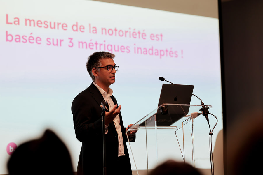Un intervenant devant la phrase « La mesure de la notoriété est basée sur 3 métriques inadaptées ! ».