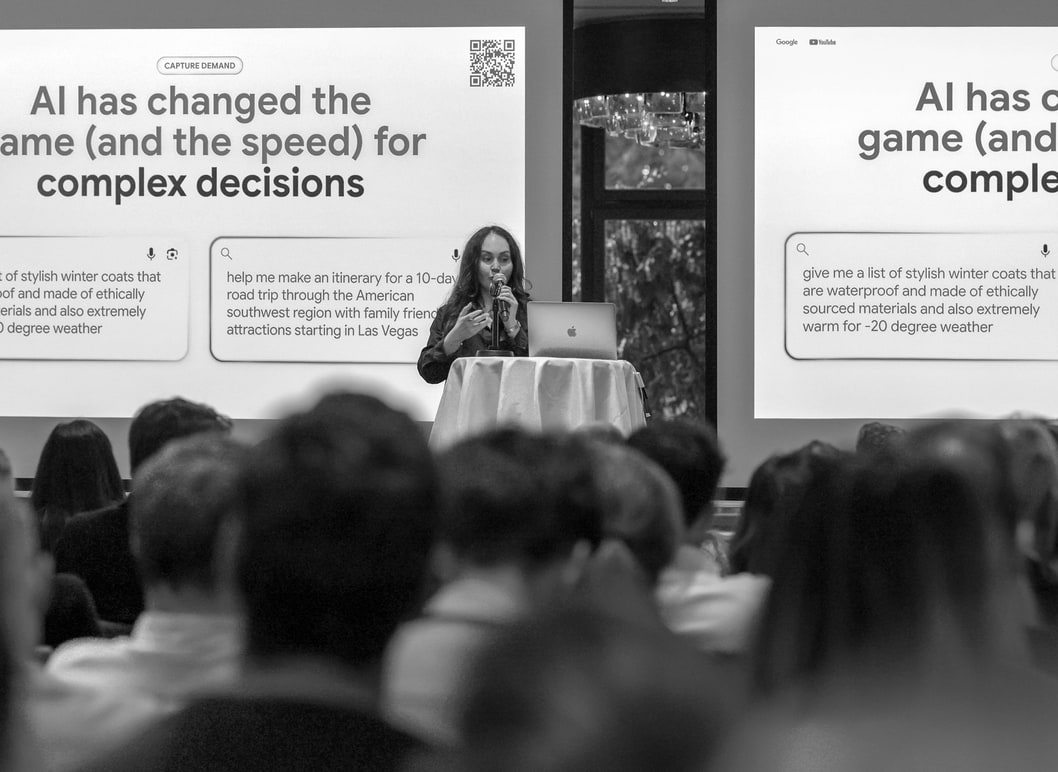 Photo en noir et blanc du public devant l’écran : « AI has changed the game (and the speed) for complex decisions ».