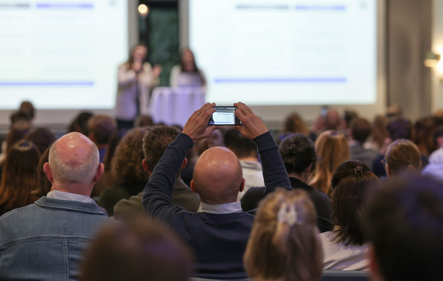 Le public de dos, un téléphone levé pour photographier l’écran.