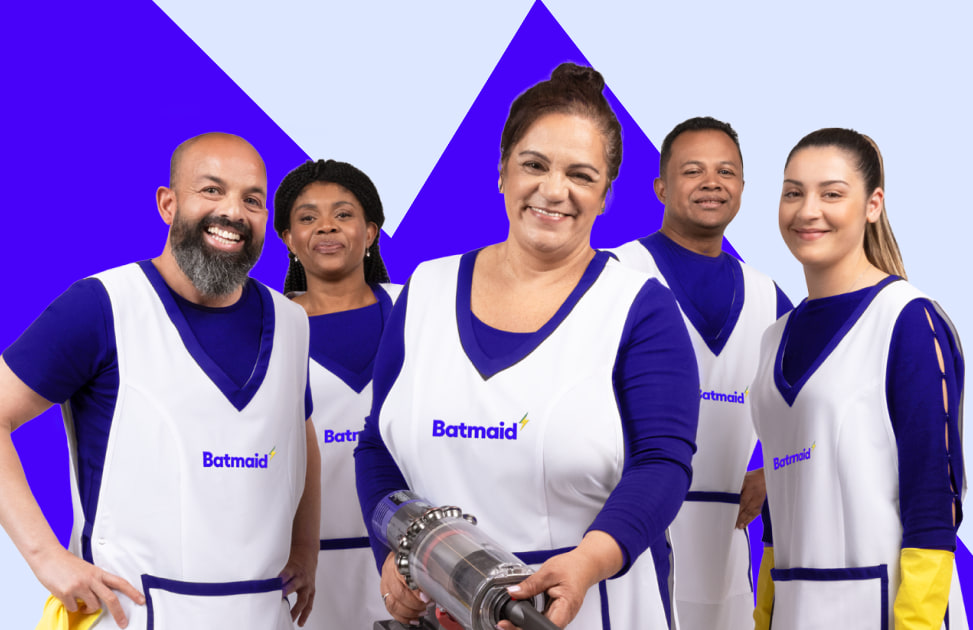 Cinq agents d’entretien souriants en tablier Batmaid, dont une femme tenant un aspirateur