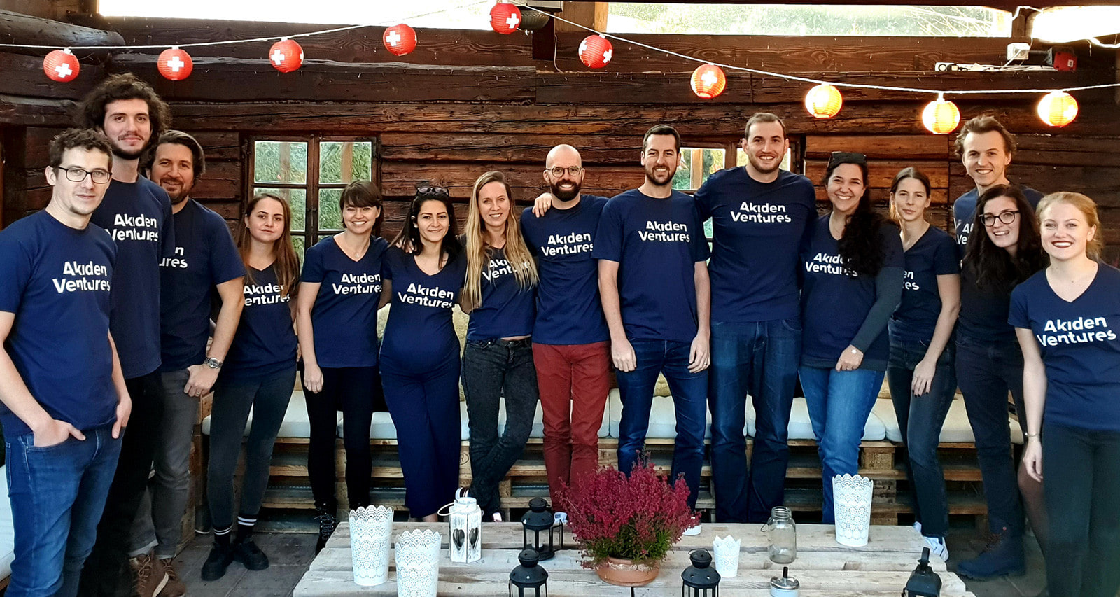 Équipe d’Akiden Ventures posant en t-shirts assortis dans un chalet décoré de lampions suisses