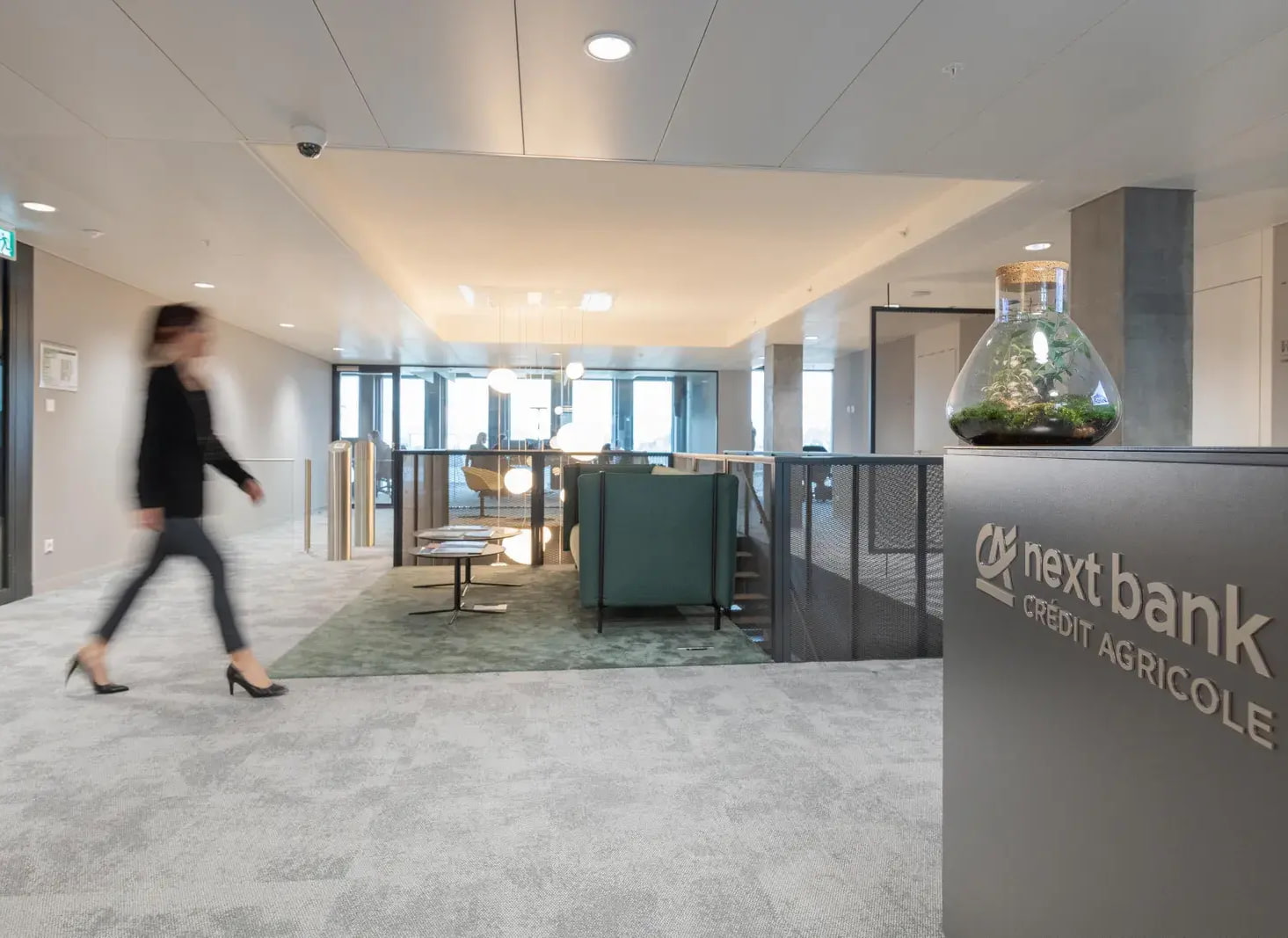 Espace d’accueil lumineux des bureaux next bank Crédit Agricole, traversé par une collaboratrice