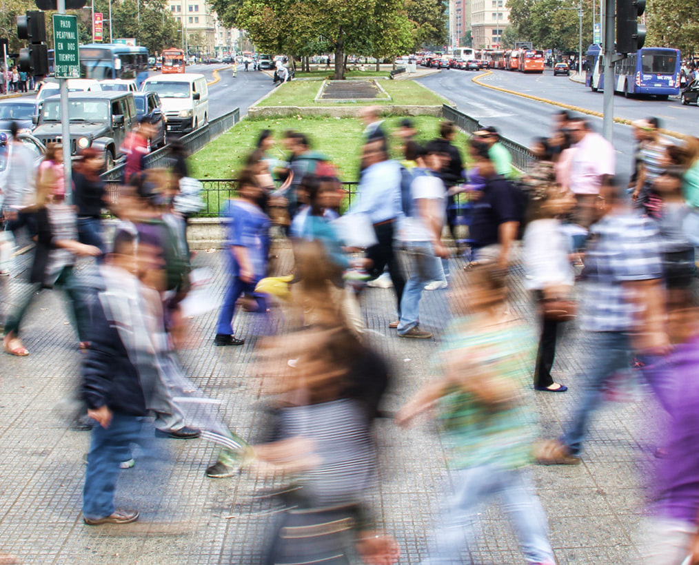 Une foule traverse une avenue, saisie en pose longue : les silhouettes se brouillent.