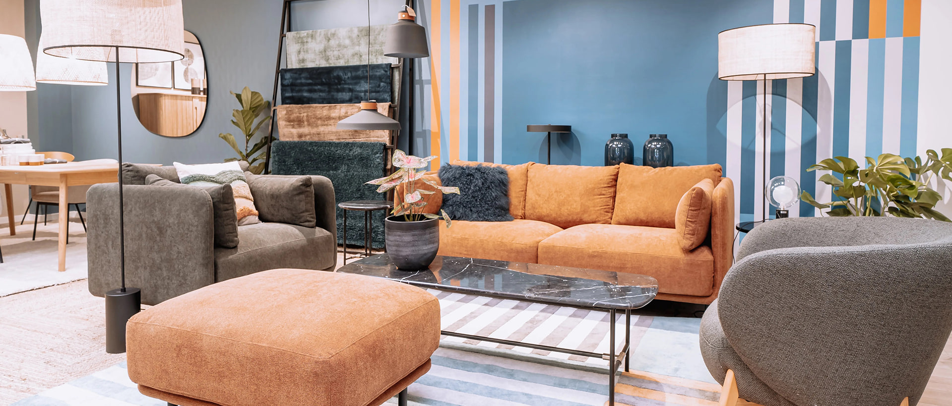 Salon aménagé avec canapé et pouf orange, fauteuils gris et table basse en marbre