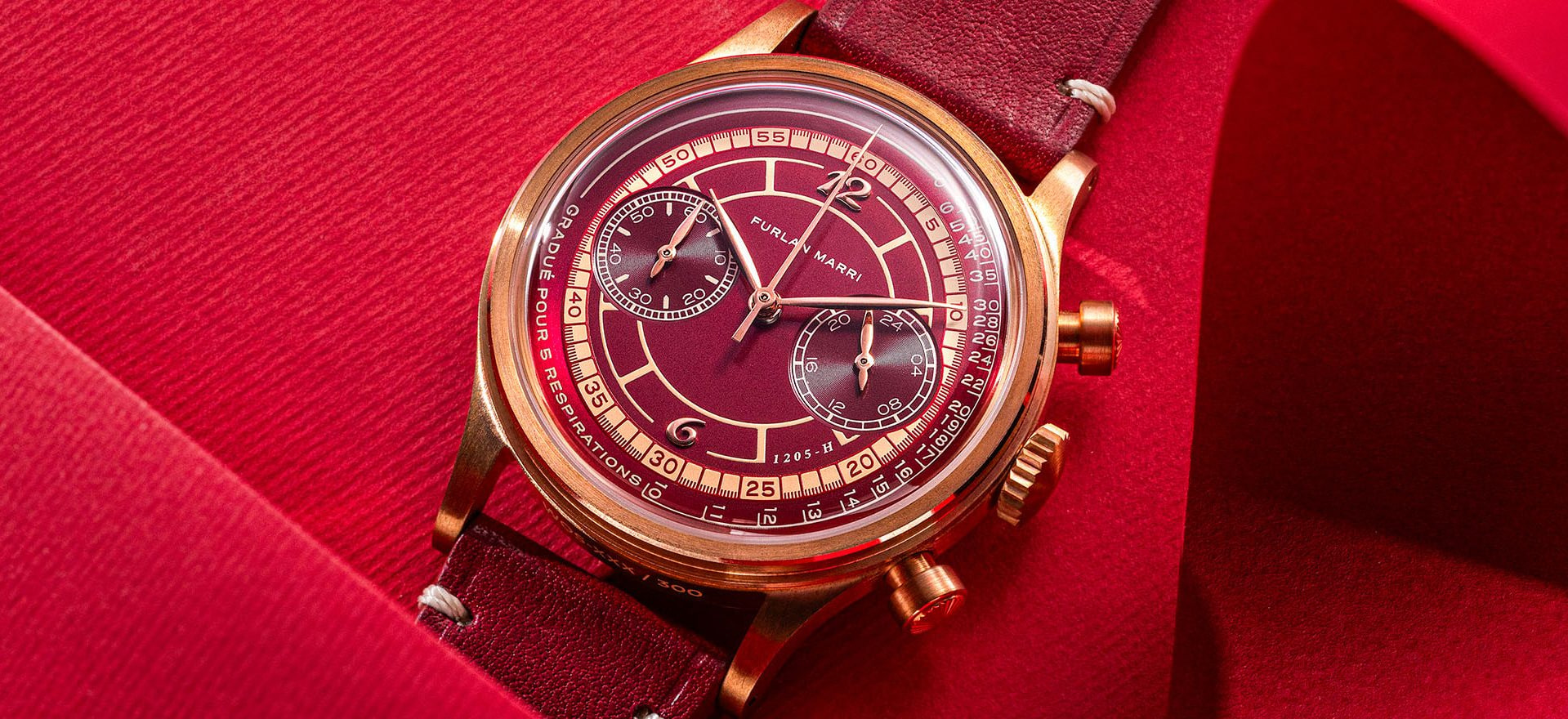 Chronographe Furlan Marri à cadran bordeaux et boîtier doré posé sur un tissu rouge