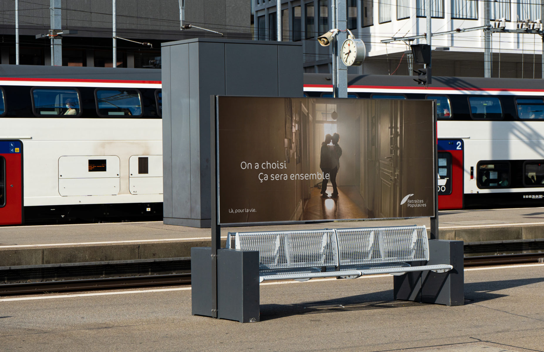 Affiche Retraites Populaires sur un quai de gare « On a choisi. Ça sera ensemble », avec un couple enlacé